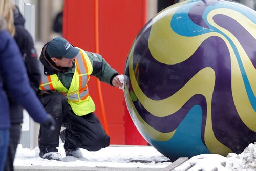 Downtown Biz employee David Messenger cleans and polishes spheres on Portage Ave. near the MTS Centre. from the web: There are sixteen 3 marbles and five 46 diameter marbles along Portage. The marbles are made out of six different colours of gel coat resin that is sprayed into two separate mould halves. The two pieces are then glued together forming the sphere. The ball is then sanded to get rid of any imperfections and the seam finished/smoothed over with bondo. The designs were then taped out and painted onto the marbles with automotive paint. The glowing lights are achieved from the natural gel coat colour that is covered with two to three layers of top coat. A 100 Watt bulb is placed inside the marble to create the glowing effect. They were installed by groundhog anchors. The plants are planted in a felt pocket inside the marble. The Marbles on Portage project was officially opened at noon on July 31, 2012 with ice cream and marble give-aways in Air Canada Park. BORIS MINKEVICH / WINNIPEG FREE PRESS  December 2, 2013