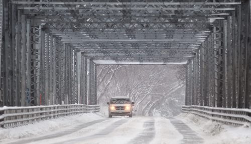 A lone vehicle drives over the Redwood Bridge as the snow continues to fall Wednesday morning.  131204 - December 4, 2013 MIKE DEAL / WINNIPEG FREE PRESS