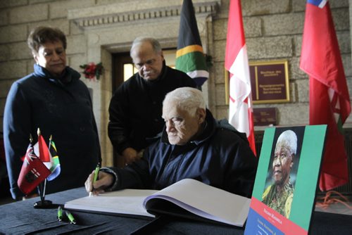 Bill Rhoda (seated) along with his son Stan Rhoda and daughter-in-law Helen Rhoda  sign the book of condolences for the late Nelson Mandela in the foyer of the Manitoba Legislative building Friday. Bill Rhoda attended the University of Fort Hare at the same time as  Nelson Mandela.  Larry Kusch story  Wayne Glowacki / Winnipeg Free Press Dec.6 2013