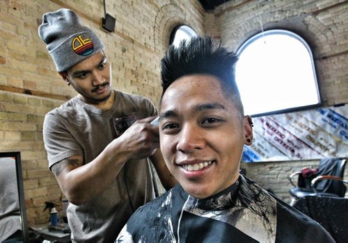 Jeremy Espiritu gets his hair cut by Mark Antonio from The Weekend Hair Salon at the former Republic NightClub, now known as The Exchange Event Center. A 12 Hour Barber Shop and Salon Marathon to raise funds for Typhoon Haiyan relief is featuring local Barbers, Hairstylists, Estheticians, and Massage Therapists - all providing their services for 12 hours. 131208 December 8, 2013 Mike Deal / Winnipeg Free Press