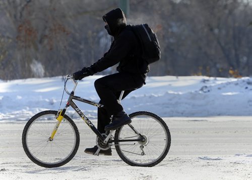 Stdup Weather  , Cyclist covered from head to toe leaving only a narrow slit to see , navigates  the snow covered  roadway on Portage Ave  during the afternoon deep freeze- Dec. 9 2013 / KEN GIGLIOTTI / WINNIPEG FREE PRESS