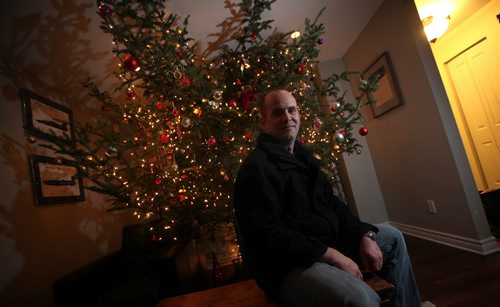 Adam Pentney poses with the bottom third of his Christmas tree display in his River Heights home. It looks like the tree is three storeys high and goes right through the roof. Its an optical illusion, of course. See Alex Paul story.  December 10, 2013 - (Phil Hossack / Winnipeg Free Press)