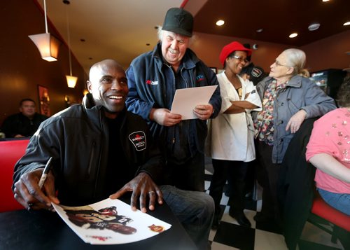 Milt Stegall and Thea Morris interact with Abe Redekop and Anna Fehr inside Thea's Diner in Morris, Manitoba. Stegall flew up from Atlanta to show support for Thea Morris in the small community, Saturday, December 14, 2013. (TREVOR HAGAN/WINNIPEG FREE PRESS)