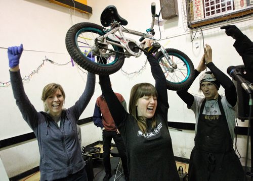 Robin Ellis (centre), a volunteer co-ordinator, cheers as she holds up the 200th bike to be repaired during the marathon. Volunteers get together at the Orioles Communtiy Centre for a 24-hour bike repair marathon. Over 250 bicycles were repaired for children whose families can't afford to buy one for Christmas. 131215 - December 15, 2013 MIKE DEAL / WINNIPEG FREE PRESS