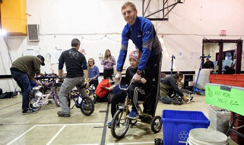 Jayson Gillespie the Manitoba Provincial Cycling Team Coach and Nathan Man, 11, test ride a tricycle after fixing it up during the marathon. Volunteers get together at the Orioles Communtiy Centre for a 24-hour bike repair marathon. Over 250 bicycles were repaired for children whose families can't afford to buy one for Christmas. 131215 - December 15, 2013 MIKE DEAL / WINNIPEG FREE PRESS