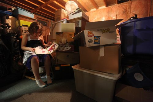 Seven year old Cadence looks at a old sticker book that she found in a box of her toys in her grandmother's basement where the families belongings are stored while  waiting to move into their new home.  The family has lived in this cramped space for over 17 months.  Photo Essay on the Van De Kaere family (including  Cadence, Shannon, Rene and Brendon) finally moving into their Habitat home just  in time for Christmas.  Dec 16, 2013 Ruth Bonneville / Winnipeg Free Press