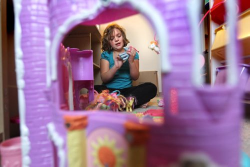 Seven year old Cadence  plays with toys that had been in storage for a year and a half on the floor of her new bedroom. Photo Essay on the Van De Kaere family (including  Cadence, Shannon, Rene and Brendon) finally moving into their Habitat home just  in time for Christmas.  Dec 16, 2013 Ruth Bonneville / Winnipeg Free Press
