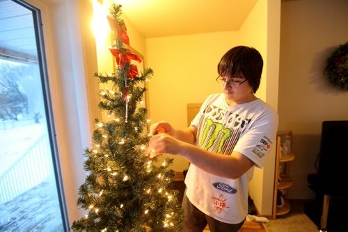 Eighteen year old Brendon helps decorated the Christmas tree in their new home in Elmwood.  Photo Essay on the Van De Kaere family (including  Cadence, Shannon, Rene and Brendon) finally moving into thier Habitat home just  in time for Christmas.  Dec 16, 2013 Ruth Bonneville / Winnipeg Free Press