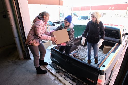 Grade seven and eight students from Woodlands Elementary, Ciarra de Laroque, 12 (left), Kelsey Henry, 13 (centre) and Ryenn Lobb, 13 (right), load up a truck on their second trip of the day to deliver hampers to those who need them. 131217 - December 17, 2013 MIKE DEAL / WINNIPEG FREE PRESS