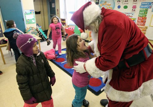Madyson Bruneau, 6, gives Santa a hug as he meets with the Kindergarten and Grade one kids at the Sergeant Tommy Prince School on the Brokenhead Ojibway First Nation during the Santa Express tour.  131218 December 18, 2013 Mike Deal / Winnipeg Free Press