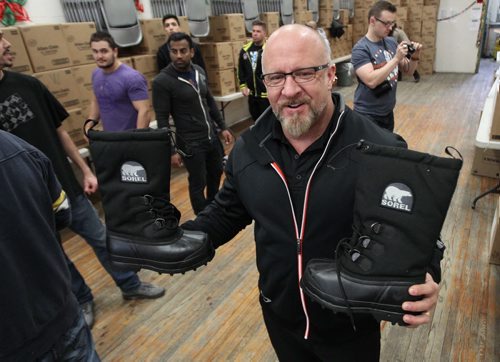Project Echo director Jeff Fisher of Elite Performance shows high quality boots, along with a number of volunteers that delivered 250 emergency hampers and 300 new pairs of winter boots to Lighthouse Mission Wednesday. The volunteers, many of them local athletes, are making a difference in meeting basic needs of some of Winnipeg's less fortunate people.- See Ashley Prest story- Dec 18, 2013   (JOE BRYKSA / WINNIPEG FREE PRESS)