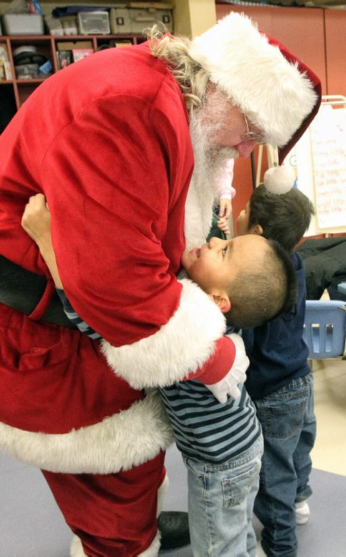 Lyle Courchene, 5, gives Santa a big hug after he arrived by by helicopter at the Black River Anishinabe School on the Little Black River First Nation with MKO Grand Chief David Harper during the Santa Express tour.  131218 December 18, 2013 Mike Deal / Winnipeg Free Press