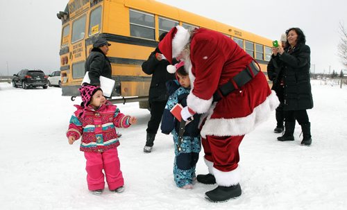 Late arrivals manage to sneak in some hugs as Santa heads out to the helicopter after visiting the Black River Anishinabe School on the Little Black River First Nation with MKO Grand Chief David Harper during the Santa Express tour.  131218 December 18, 2013 Mike Deal / Winnipeg Free Press