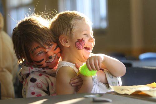 Seven year old Elizabeth Terry (left, Tiger face) giggles and tickles her friend Maci Jacobs - 3 and a half, as they open and  play with gifts given out to them at the annual Salvation  Army breakfast Saturday morning.  Dec 7, 2013 Ruth Bonneville / Winnipeg Free Press