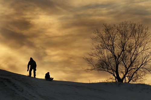 December 21, 2013 - 131221  -  A father pushes his son down "Garbage Hill" at Westview Park amid a setting sun Saturday, December 21, 2013. JOHN WOODS / WINNIPEG FREE PRESS. weather