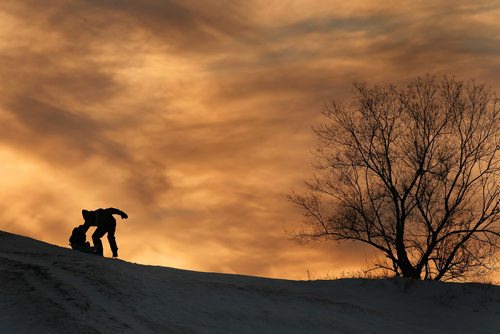 December 21, 2013 - 131221  -  A father pushes his son down "Garbage Hill" at Westview Park amid a setting sun Saturday, December 21, 2013. JOHN WOODS / WINNIPEG FREE PRESS. weather