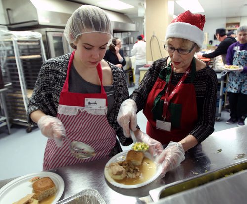 Volunteers Hannah Taylor, left, and Carol Cockrell in the kitchen working hard at Christmas Eve dinner at the Siloam Mission this afternoon- 500 guests will be served by 110 volunteers eating 95 turkeys, 450 lbs of potatoes, and 85 pies- Standup photo- Dec 24, 2013   (JOE BRYKSA / WINNIPEG FREE PRESS)