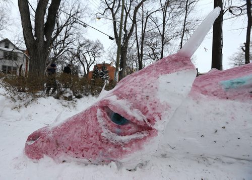 Pedestrians walk past Joe Schwarz's 25-foot-long sleeping dragon sculpture made of coloured snow and ice on Wolseley Avenue on Thurs., Dec. 26, 2013. Photo by Jason Halstead/Winnipeg Free Press