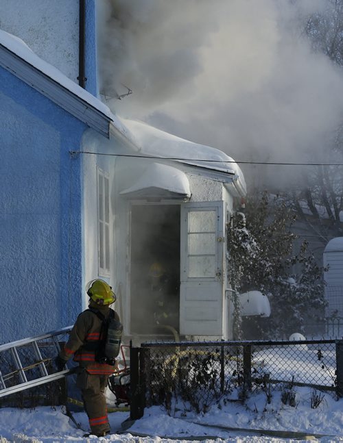 WFS firefighter feeds hose through the back door of the house  on his hands and knees  , House Fire 406 Manitoba Ave. At Salter St. just before 3pm Tuesday  - The fire broke out in the second floor of the two story house , heavy smoke billowed from the house and WFS quickly put the fire out  and  there are no injuries , Dec. 31 2013 / KEN GIGLIOTTI / WINNIPEG FREE PRESS