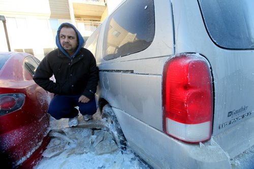 Rupinder Dhaliwal stands on a block of ice next to his vehicle that froze to the ground when a  water main broke in the parking lot next to his apartment on New Years Eve Day on Jefferson. Jan 02, 2014 Ruth Bonneville / Winnipeg Free Press