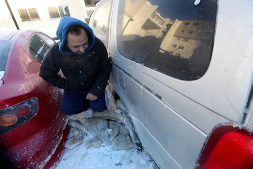 Rupinder Dhaliwal stands on a block of ice next to his vehicle that froze to the ground when a  water main broke in the parking lot next to his apartment on New Years Eve Day on Jefferson. Jan 02, 2014 Ruth Bonneville / Winnipeg Free Press