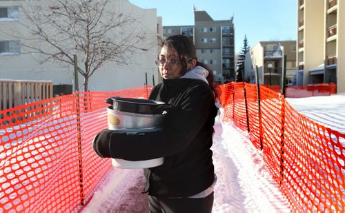 Twenty Two year old Vanessa Singh walks back to her apartment with large pots that she filed with boiling water and poured on her tires to try and free her car from the parking lot that filled with water after a water main break on New Years Eve left dozens of  vehicles frozen to knee deep ice. See story. Jan 02, 2014 Ruth Bonneville / Winnipeg Free Press