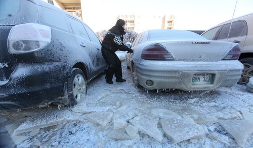 Maryanne Katyrynuik tries to open the door of her vehicle that  froze to the ground when a  water main broke in the parking lot next to his apartment on New Years Eve Day on Jefferson. Jan 02, 2014 Ruth Bonneville / Winnipeg Free Press