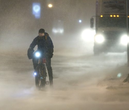An all weather cyclist waits for traffic lights to change while the snow swirls around Portage Ave. at Fort St. Friday morning. weather web story Wayne Glowacki / Winnipeg Free Press Jan.3 2014