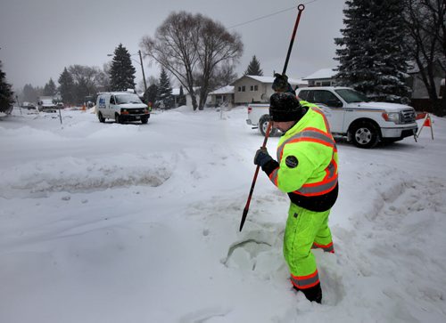 A city worker probes for a manhole cover buried in snow along Laxdal rd in Charleswood Friday afternoon. See Kevin Rollason story. January 3, 2014 - Phil Hossack / Winnipeg Free Press)