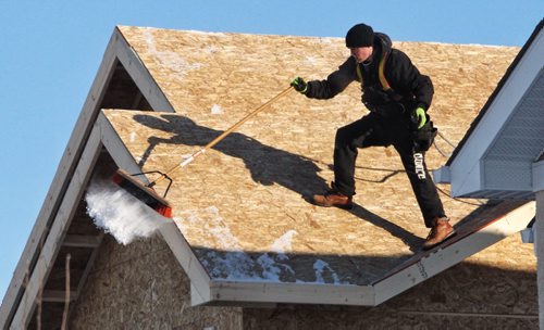 A construction worker cleans off the roof of a house being built in the Bridgewater Lakes development. 140108 - January 8, 2014 MIKE DEAL / WINNIPEG FREE PRESS