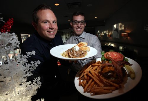 The Oakwood Cafe. Partners Peter Paley (left) and Alix Loiselle hold their favorite dishes, Beef Stroganoff and the Oakwood Burger respectively. Dave  Sanderson has written an anecdotal history of the Oakwood, a breakfast / lunch /dinner nook in trendy south Osborne - was one of the first restaurants in the area - shots of exterior and of owner Peter Paley and his partner Alix Loiselle. January 8, 2014 - (Phil Hossack / Winnipeg Free Press)
