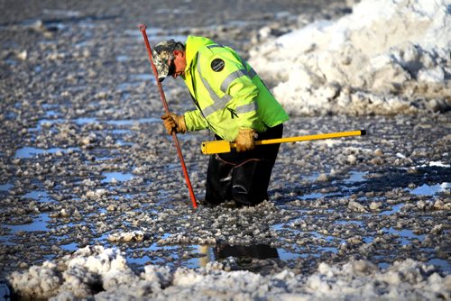 City of Winnipeg worker looks for blocked man-hole in knee-deep water on Holden Street just off Marion Ave. Thursday afternoon after a water main break caused flooding on roads in area and closing down Marion Street just west of Lagimodiere Blvd  Jan 09, 2014 Ruth Bonneville / Winnipeg Free Press