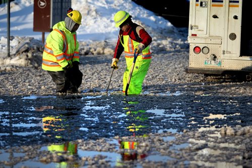 City of Winnipeg workers try  to find and lift a man-hole cover on Holden Street just off Marion Ave. Thursday afternoon after a water main break caused flooding on roads in area and closing down Marion Street just west of Lagimodiere Blvd  Jan 09, 2014 Ruth Bonneville / Winnipeg Free Press
