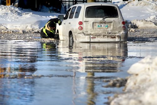 A tow truck driver with Tartan immerses himself in hip deep water as he works to get a driver out of the water  on Holden Street just off Marion Ave. Thursday afternoon after a water main break caused flooding on roads in area and closing down Marion Street just west of Lagimodiere Blvd  Jan 09, 2014 Ruth Bonneville / Winnipeg Free Press