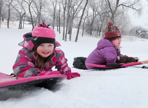 Five year old Emily Aikman smiles as she pushes her sled up Omands Creek hill with her friend  Mya Tottle , also five, Saturday morning while enjoying the warm winter weather with their families. Standup photo  Jan 11,, 2014 Ruth Bonneville / Winnipeg Free Press