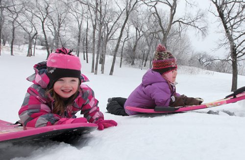 Five year old Emily Aikman (left)  smiles as she pushes her sled up Omands Creek hill with her friend  Mya Tottle , also five, Saturday morning while enjoying the warm winter weather with their families. Standup photo  Jan 11,, 2014 Ruth Bonneville / Winnipeg Free Press