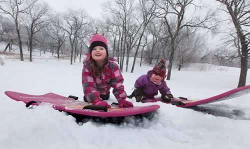 Five year old Emily Aikman (left)  smiles as she pushes her sled up Omands Creek hill with her friend  Mya Tottle , also five, Saturday morning while enjoying the warm winter weather with their families. Standup photo  Jan 11,, 2014 Ruth Bonneville / Winnipeg Free Press