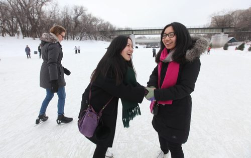 Lingbo Zhou (left) and her friend Lingyan Mao both students from China studying in Winnipeg try ice skating for the first time  on the new Red River Mutual Trail on the Assiniboine River at the Forks Saturday afternoon.  Hundreds of  Winnipegers made their way down to the river to enjoy the newly opened river trail and the balmy winter weather.  Jan 11,, 2014 Ruth Bonneville / Winnipeg Free Press
