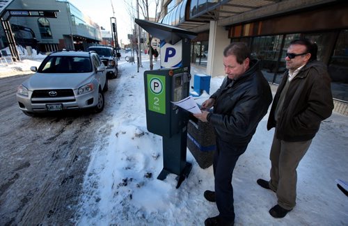 Frustrated by one Kennedy Streeet paystation Perry Rougeau tries a third credit card trying to get this one to work. A shivering Manaour Rajabi waits to try his luck. Both eventually got the machine to work. See story January 22, 2014 - (Phil Hossack / Winnipeg Free Press)