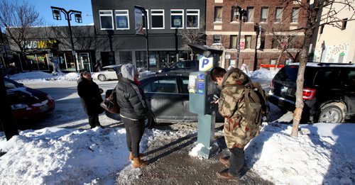Alex Limit plugs payment into a Graham ave paystation to extend his time Wednesday. A pair of other parking patrons wait in line to use the paystation, one of two on the block, the only one in working condition. See story January 22, 2014 - (Phil Hossack / Winnipeg Free Press)