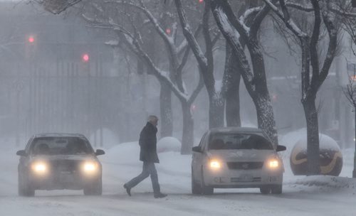 A pedestrian crosses Portage Avenue Sunday morning as gusts of snow create low visibility.  140126 - January 26, 2014 MIKE DEAL / WINNIPEG FREE PRESS