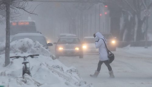 A pedestrian crosses Portage Avenue Sunday morning as gusts of snow create low visibility.  140126 - January 26, 2014 MIKE DEAL / WINNIPEG FREE PRESS