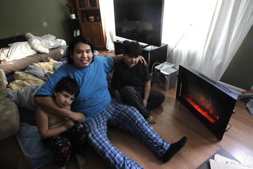 Derek Dowan and his two sons Dave,6 at left, and Daniel,9, keep toasty warm by the electric heater and heat from the kitchen stove in their home with out natural gas in Niverville Mb.Monday morning. It was 4C when the family woke up sleeping after sleeping in the living room. Adam Wazny  story  Wayne Glowacki / Winnipeg Free Press Jan.27  2014