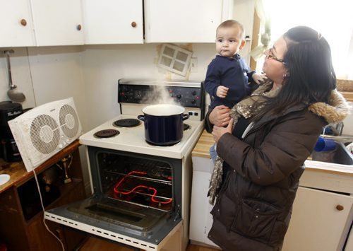Rachelle Vincent with son Nicholas, 8 months old in their kitchen of their home in St-Pierre-Jolys, Manitoba heated by the stove and portable heaters after the natural gas explosion in Otterburne,Mb. last weekend. Adam Wazny  story  Wayne Glowacki / Winnipeg Free Press Jan.27  2014