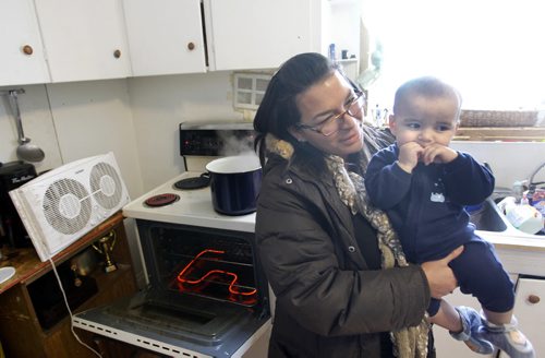 Rachelle Vincent with son Nicholas, 8 months old in their kitchen of their home in St-Pierre-Jolys, Manitoba heated by the stove and portable heaters after the natural gas explosion in Otterburne,Mb. last weekend. Adam Wazny  story  Wayne Glowacki / Winnipeg Free Press Jan.27  2014