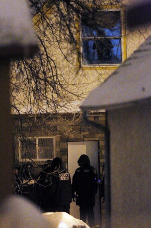 SHOOTING SCENE back lane behind 642 Magnus in the north end. House on Manitoba that the police surrounded. Someone looking out the window above the police. BORIS MINKEVICH / WINNIPEG FREE PRESS. JAN 30, 2014