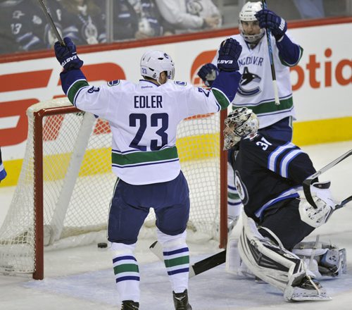Winnipeg Jets goaltender Ondrej Pavelec looks at goal in net as Vancouver h Canucks Alexander Elder celebrates his first period NHL action in Winnipeg Friday night -See story- Jan 31, 2014   (Fred Greenslade  / Special for the WINNIPEG FREE PRESS)