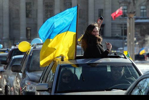 Daria Lytwyn tries to get a quick photo of the procession while her car is stopped at a light during a car rally. The Ukrainian Canadian Congress - Manitoba Provincial Council held an Auto-Maidan Car Rally through the streets of Winnipeg. Local Ukrainians rallied to raise awareness about the situation in Ukraine and showing solidarity with the Ukrainian people. The Auto-maidan movement in Ukraine, is one of the most visible expressions of public discontent with the regime. 140209 - February 09, 2014 MIKE DEAL / WINNIPEG FREE PRESS