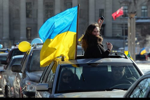 Daria Lytwyn tries to get a quick photo of the procession while her car is stopped at a light during a car rally. The Ukrainian Canadian Congress - Manitoba Provincial Council held an Auto-Maidan Car Rally through the streets of Winnipeg. Local Ukrainians rallied to raise awareness about the situation in Ukraine and showing solidarity with the Ukrainian people. The Auto-maidan movement in Ukraine, is one of the most visible expressions of public discontent with the regime. 140209 - February 09, 2014 MIKE DEAL / WINNIPEG FREE PRESS