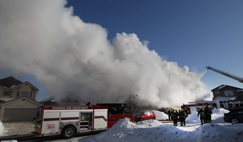 Firefighters in defensive mode stand back as aerial ladder shoots water  at a fire today on Ed Golding Bay in Transcona- The home is a total loss with officials pegging damage at $400,000-    See story- Feb 10, 2014   (JOE BRYKSA / WINNIPEG FREE PRESS)